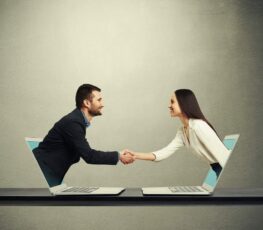 A image of two people shaking hands through the computer.