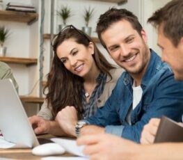 An image of 3 people looking at a computer.