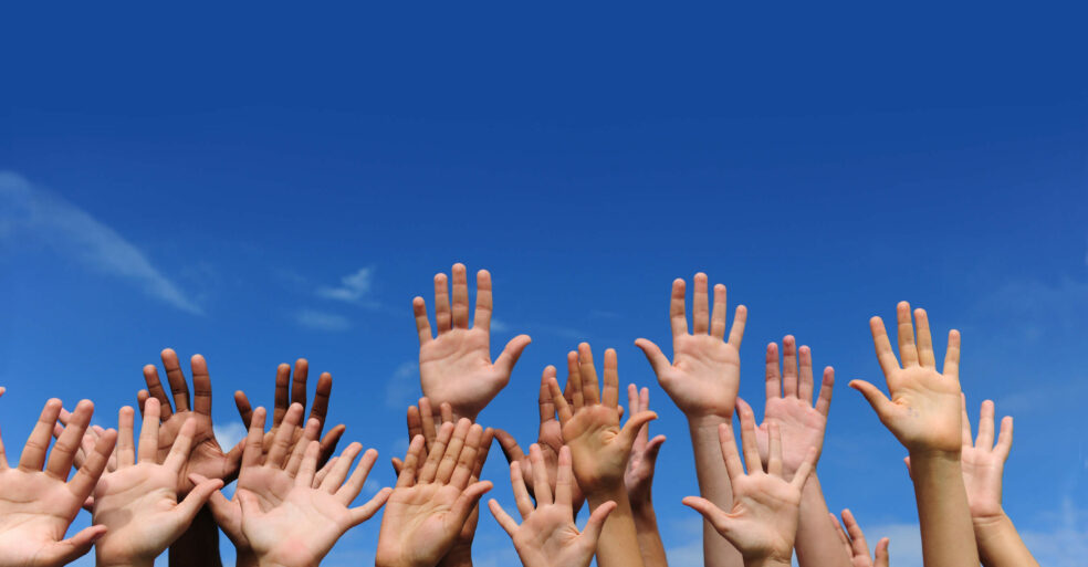 An image of multiple hands raised in the air.