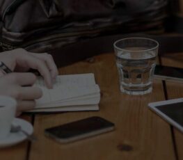 A glass of water and notebook at a table.