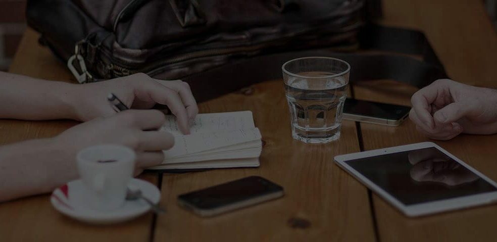 A glass of water and notebook at a table.